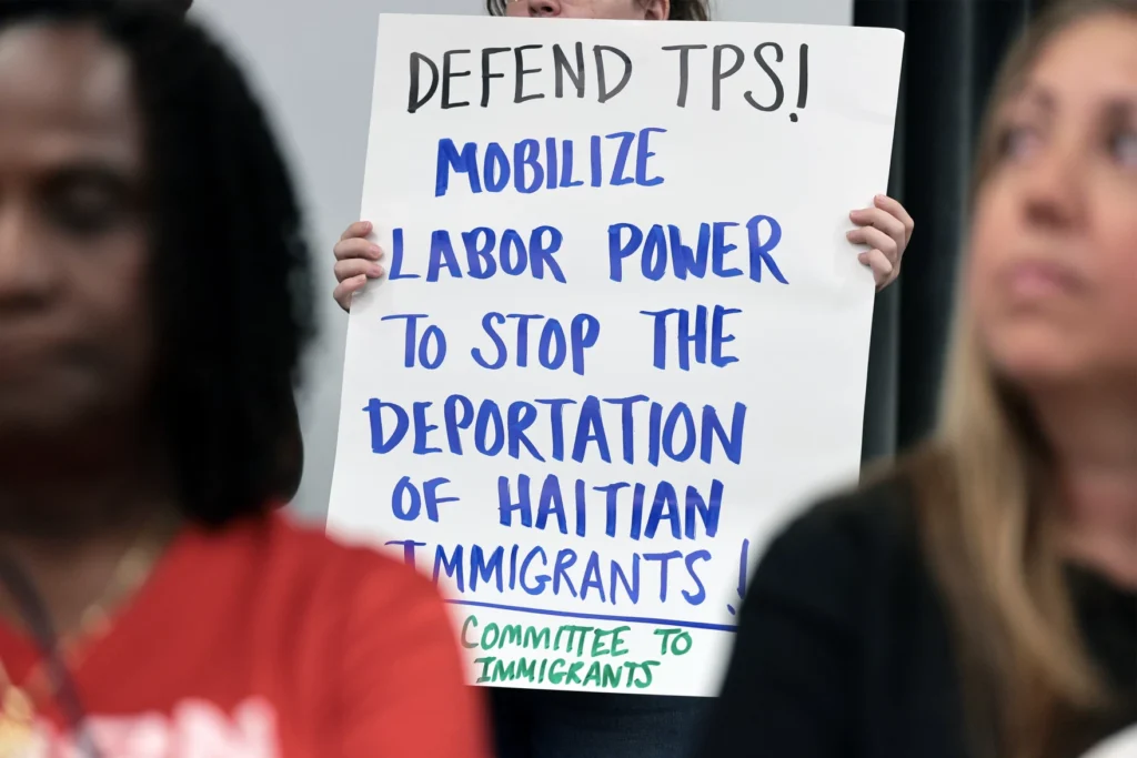 People hold signs during a press conference on the end of the Temporary Protected Status (TPS)
